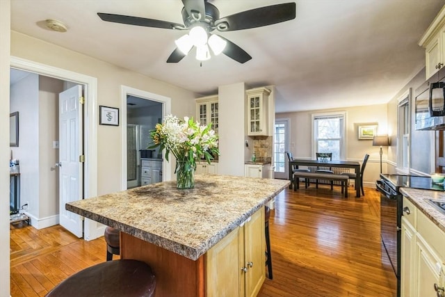 kitchen with dark hardwood / wood-style flooring, a center island, electric range, and a kitchen bar