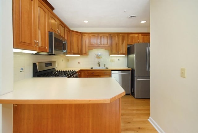 19 Concord Greene Unit 3, Concord, MA 01742 - kitchen with stainless steel appliances, a peninsula, light countertops, light wood-type flooring, and tasteful backsplash