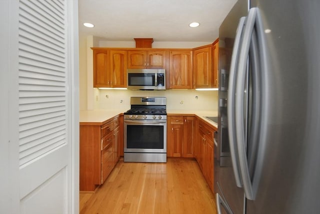 19 Concord Greene Unit 3, Concord, MA 01742 - kitchen featuring appliances with stainless steel finishes, light wood finished floors, light countertops, brown cabinetry, and recessed lighting