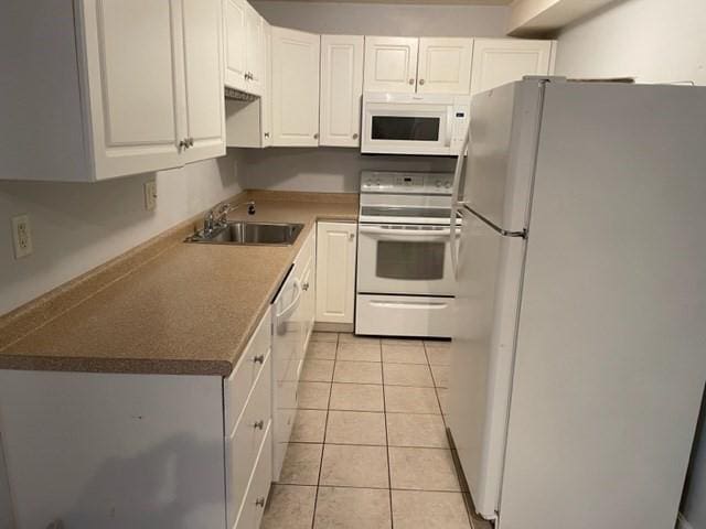 kitchen featuring white appliances, a sink, white cabinetry, and light tile patterned flooring