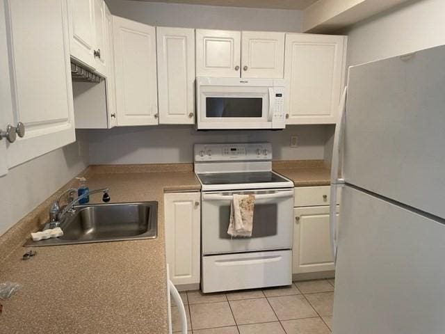 kitchen with white appliances, a sink, white cabinets, and light tile patterned floors