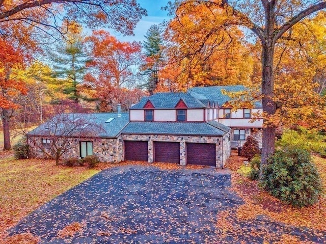 242 Eastwood Dr, Westfield, MA 01085 - tudor-style house with asphalt driveway, stone siding, and an attached garage