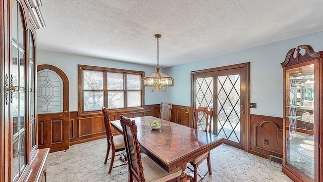 242 Eastwood Dr, Westfield, MA 01085 - dining space with wainscoting, a textured ceiling, a chandelier, wood walls, and light colored carpet
