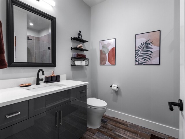 bathroom with vanity, toilet, wood-type flooring, and a shower