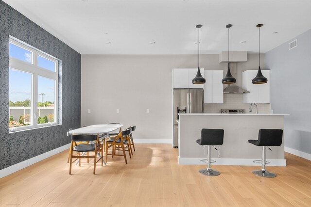 kitchen with light hardwood / wood-style floors, decorative light fixtures, backsplash, and white cabinets