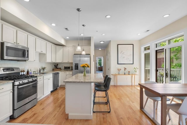 129 Highland Ave Unit 4, Somerville, MA 02143 - kitchen featuring stainless steel appliances, a center island, light wood-style floors, white cabinetry, and recessed lighting