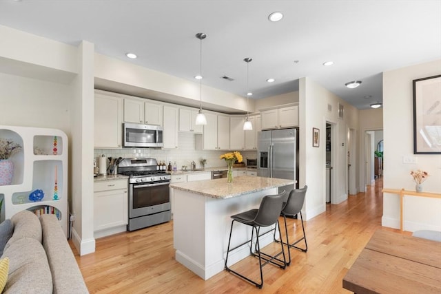 129 Highland Ave Unit 4, Somerville, MA 02143 - kitchen with appliances with stainless steel finishes, a kitchen bar, tasteful backsplash, light stone countertops, and a center island