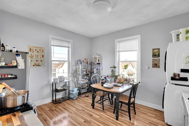 dining space featuring stacked washer and clothes dryer, light hardwood / wood-style flooring, and plenty of natural light