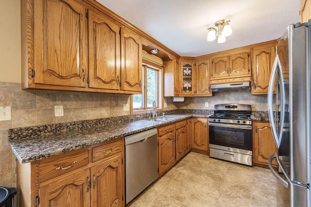 1170 E St, Ludlow, MA 01056 - kitchen featuring stainless steel appliances, under cabinet range hood, brown cabinetry, and tasteful backsplash