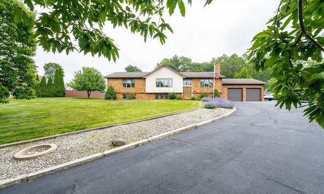 1170 E St, Ludlow, MA 01056 - view of front facade featuring a chimney, driveway, an attached garage, and brick siding