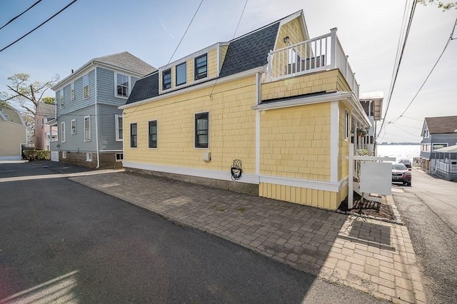 view of property exterior with a balcony and roof with shingles