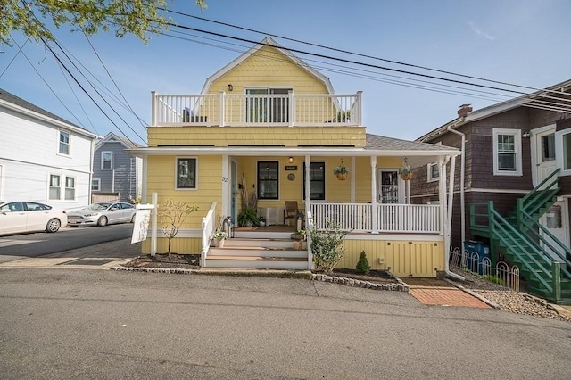 view of front of home featuring covered porch, stairway, and a balcony