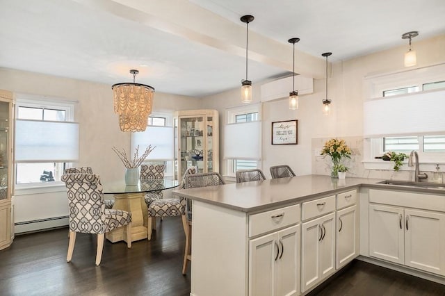 kitchen with dark wood finished floors, a sink, a baseboard heating unit, an inviting chandelier, and white cabinetry