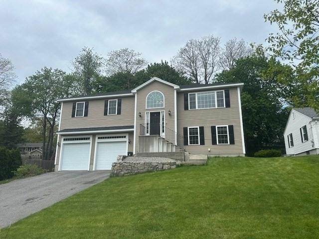 bi-level home featuring an attached garage, driveway, and a front lawn