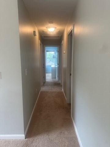 hall featuring light colored carpet and baseboards