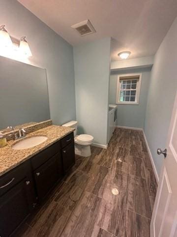 bathroom featuring wood finished floors, toilet, vanity, and baseboards