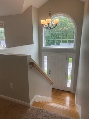 foyer featuring a chandelier, high vaulted ceiling, wood finished floors, and baseboards
