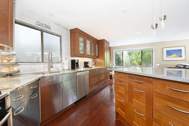 kitchen featuring stainless steel dishwasher, a sink, glass insert cabinets, and light stone countertops