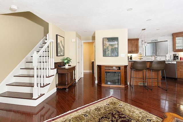 living room featuring dark wood-type flooring, stairway, and baseboards