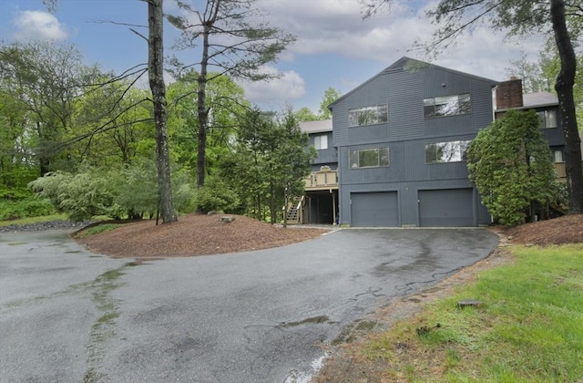 view of home's exterior with asphalt driveway, an attached garage, and stairs