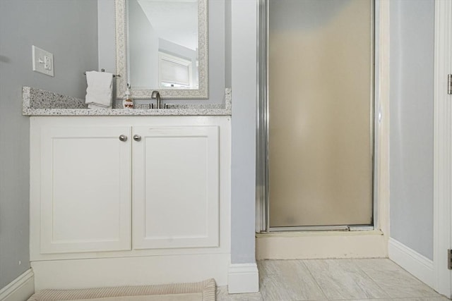 full bath with a shower stall, baseboards, and vanity