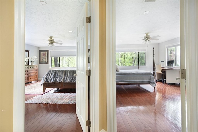 hallway featuring a textured ceiling, hardwood / wood-style floors, baseboards, and an office area