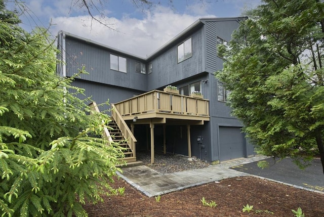 back of property featuring stairway, a deck, and an attached garage