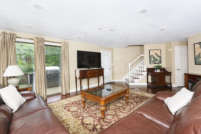 living area with baseboards, wood finished floors, and stairway
