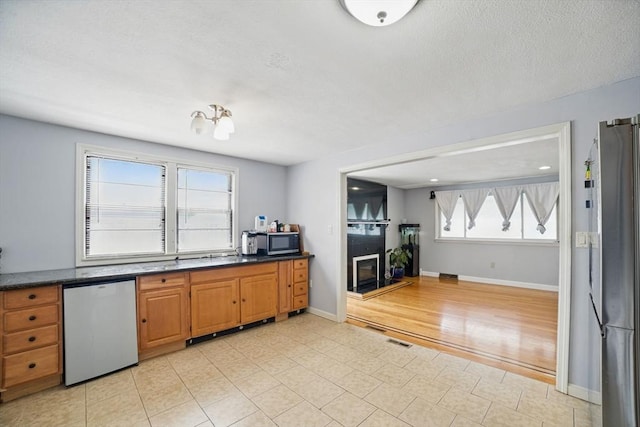 26 Hanna St, Quincy, MA 02169 - kitchen featuring appliances with stainless steel finishes, dark countertops, baseboards, and brown cabinets