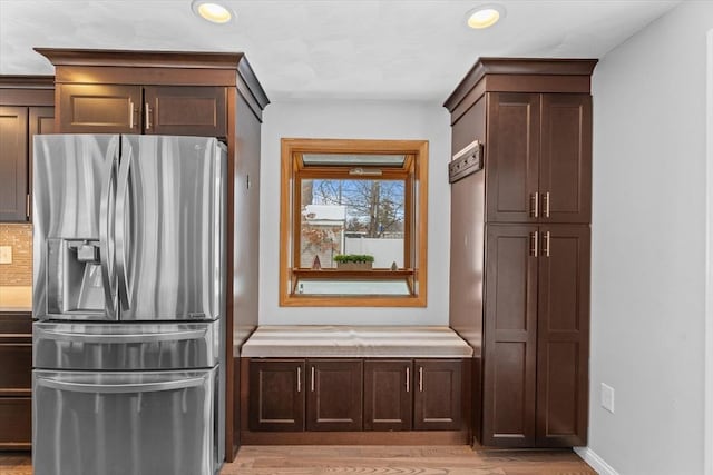 kitchen featuring dark brown cabinets, backsplash, light hardwood / wood-style floors, and stainless steel fridge