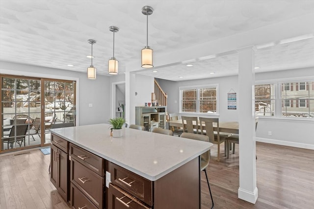 kitchen featuring decorative light fixtures, a wealth of natural light, light hardwood / wood-style flooring, and a kitchen island