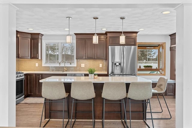 kitchen with decorative light fixtures, a center island, a wealth of natural light, and appliances with stainless steel finishes