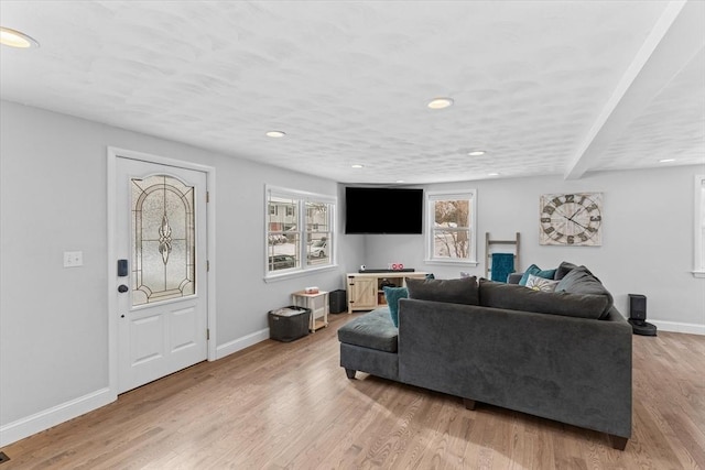 living room featuring plenty of natural light, light hardwood / wood-style flooring, and beamed ceiling