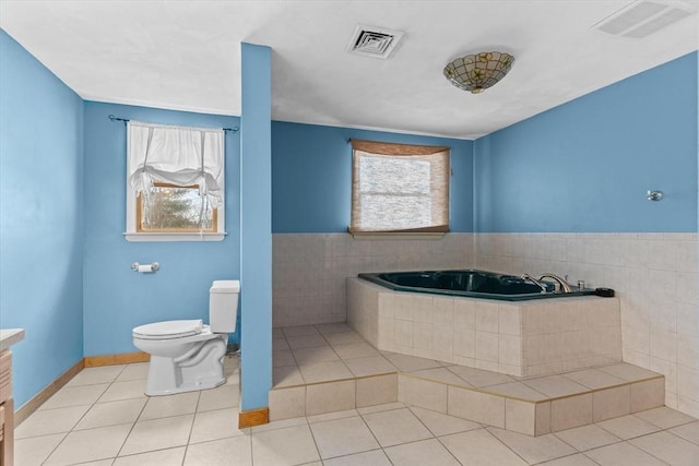 bathroom featuring vanity, toilet, a relaxing tiled tub, and tile patterned flooring