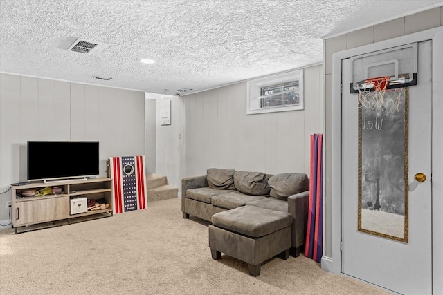 carpeted living room with wood walls and a textured ceiling