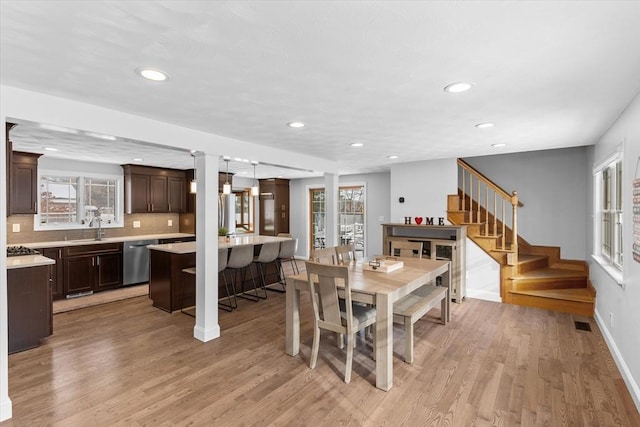 dining space with light hardwood / wood-style floors, sink, and decorative columns