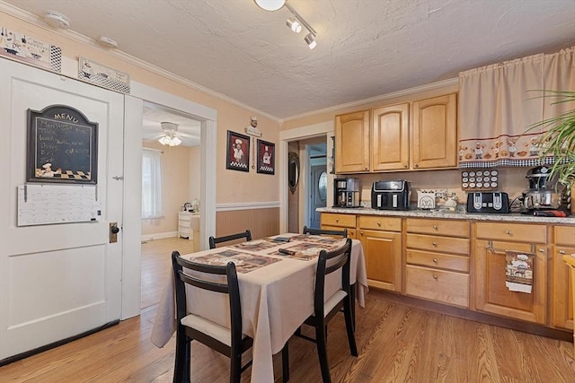 kitchen with light wood-type flooring, a wainscoted wall, light brown cabinets, a textured ceiling, and a ceiling fan