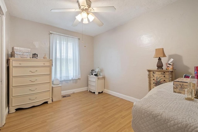 bedroom with light wood-style floors, baseboards, a textured ceiling, and a ceiling fan