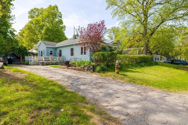 view of front of home featuring driveway, a deck, and a front yard