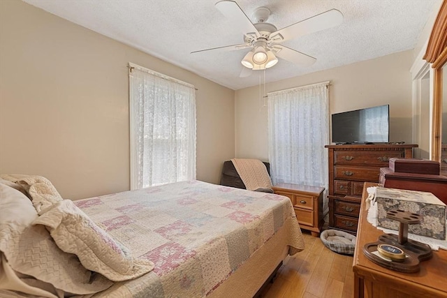 bedroom featuring light wood-style floors, a textured ceiling, and a ceiling fan