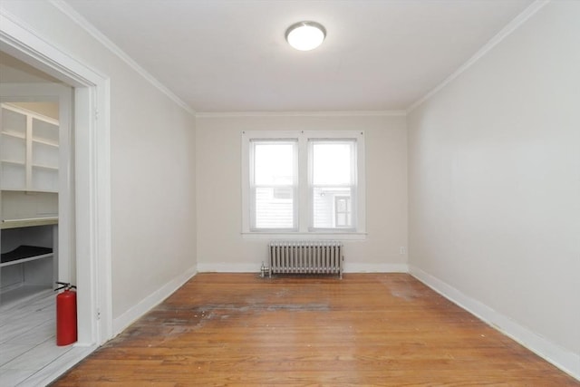 unfurnished room with hardwood / wood-style floors, radiator heating unit, and crown molding