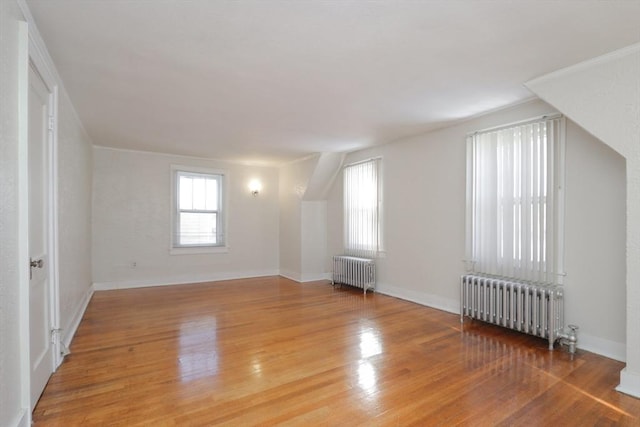 bonus room with hardwood / wood-style floors and radiator heating unit