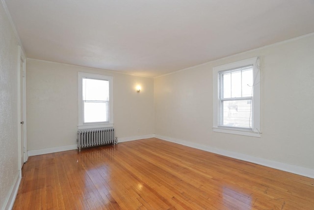 empty room featuring radiator heating unit, hardwood / wood-style floors, and ornamental molding