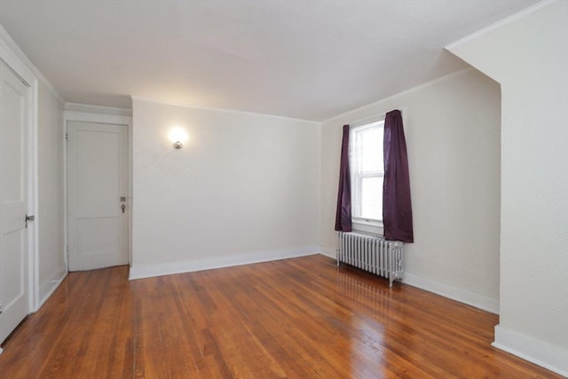 spare room with radiator heating unit, ornamental molding, and dark hardwood / wood-style floors