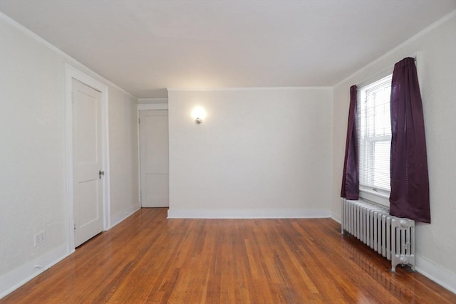 spare room with dark wood-type flooring, radiator, and ornamental molding