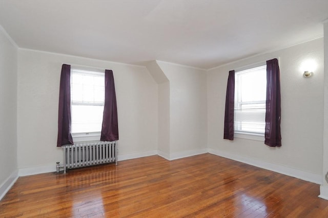 bonus room with wood-type flooring, radiator heating unit, and a healthy amount of sunlight