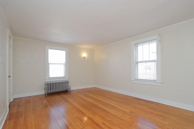 spare room featuring hardwood / wood-style flooring, radiator heating unit, and crown molding