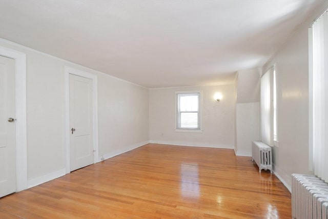 unfurnished room featuring radiator heating unit and light wood-type flooring