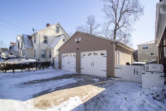 snow covered property featuring a garage and an outdoor structure