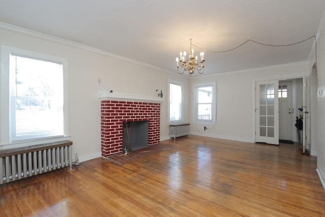 unfurnished living room with hardwood / wood-style floors, radiator, ornamental molding, and an inviting chandelier